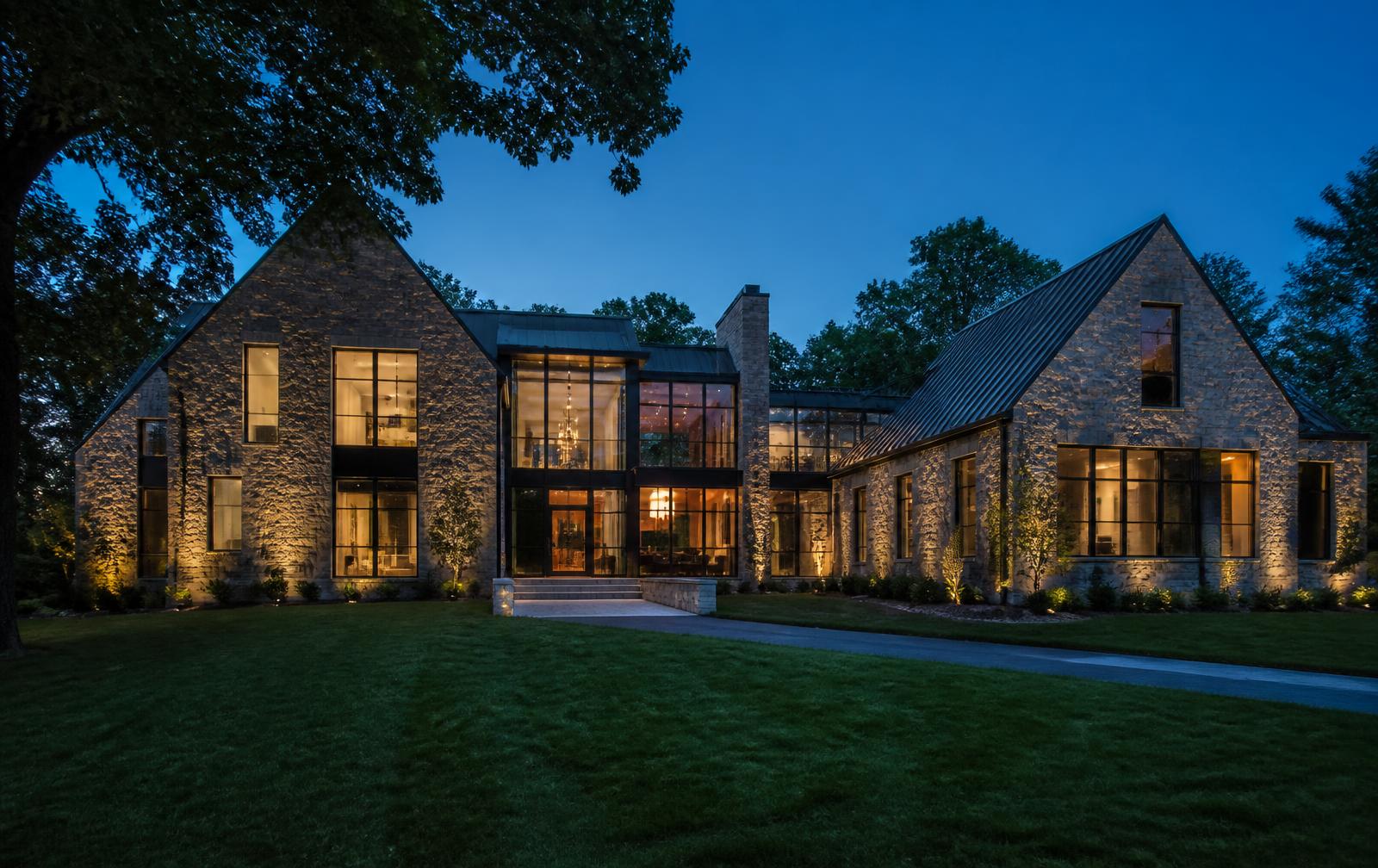 Modern luxury single-family stone and glass residence lit at dusk